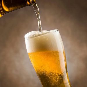 Pouring golden lager into a tilted beer glass to control foam